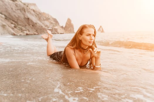 Woman travel sea. Young Happy woman in a long red dress posing on a beach near the sea on background of volcanic rocks, like in Iceland, sharing travel adventure journey