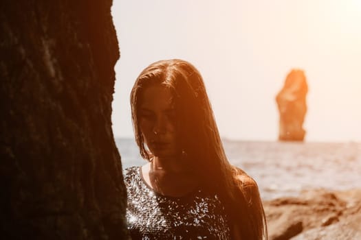 Woman travel sea. Young Happy woman in a long red dress posing on a beach near the sea on background of volcanic rocks, like in Iceland, sharing travel adventure journey