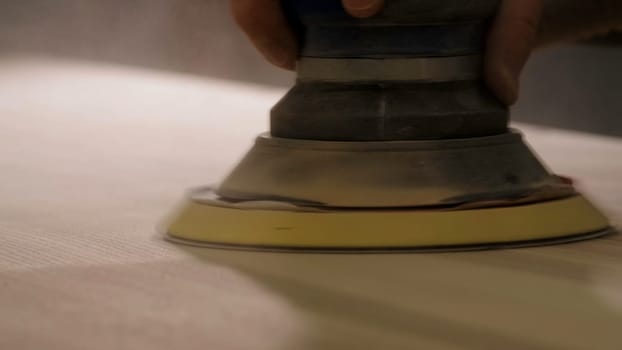 Craftsman hands polishing wooden table with machine. Creative. Man carpenter using professional equipment to polish a large board of wood