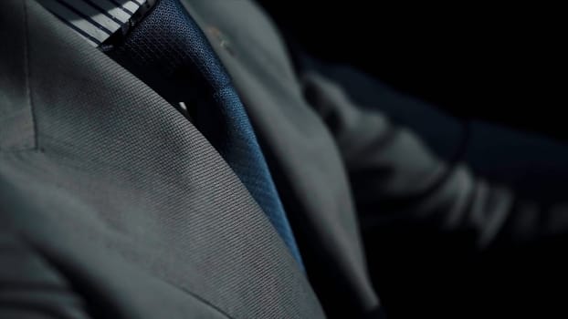 Close up of businessman in formal suit driving a car. Handsome young man sitting at wheel of car. Guy spending time in traffic jam and looking at car's interior.