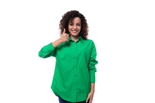 young employee of the company woman with black hair dressed in a green shirt shows like.