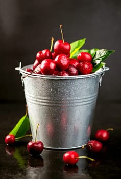 Ripe sweet cherry berry with leaves on a black wooden board
