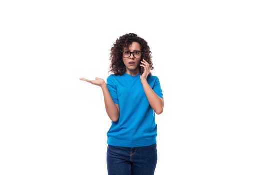 young strict leader woman with curly hair dressed in a blue t-shirt speaks on the phone.