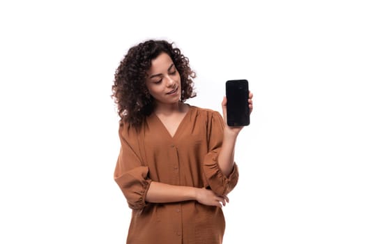 young secretary brunette woman dressed in a brown shirt shows a smartphone mockup.