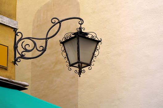 Fragment of an old Venetian building. Wall mounted street lamp and stone balcony with lion sculpture.