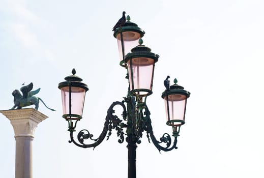 Lantern on the street of Venice. Pink lights of Venice. Four lamps with pink glass are on an ornate black metal lamp post