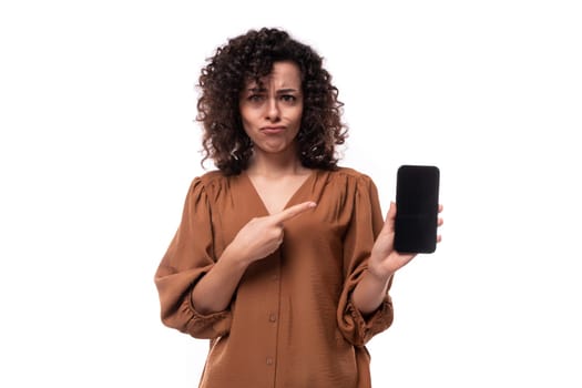 young secretary brunette woman dressed in a brown shirt shows a mock-up of a mobile phone.