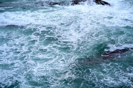 Waves crashing on seashore rocks,Top view sea surface waves background