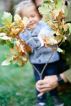 Dad holds an oak branch in his hand and a little girl holds a toy cat. High quality photo