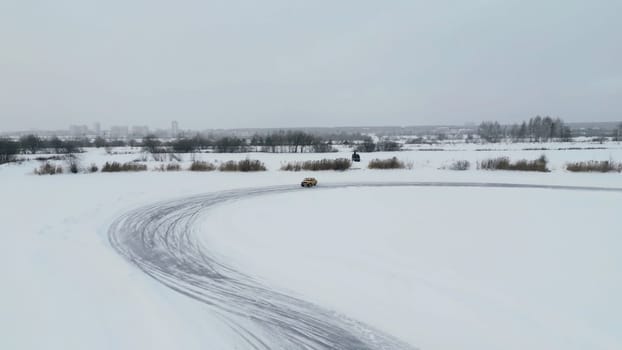 Aerial view of a driving car at snowy track at winter. Clip. One car driving through ice covered lake