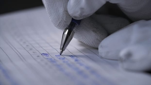 Side view of a hand making notes in a logbook. Close up of hands in white gloves writing data in the notebook with a pen on black background.
