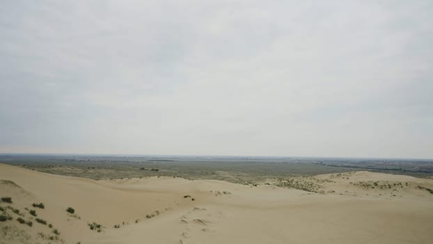 Beautiful desert mountains. Action. The desert against the white sky behind the big slightly green mountains and all in the sand