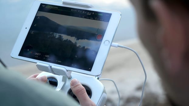 Close-up of man's hands with a remote control flying a small quadcopter toy at nature.