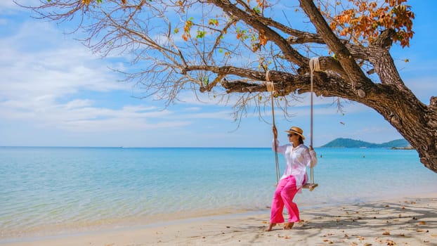 Asian woman on a swing at the beach of Koh Samet Island Rayong Thailand, the white tropical beach of Samed Island with a turqouse colored ocean