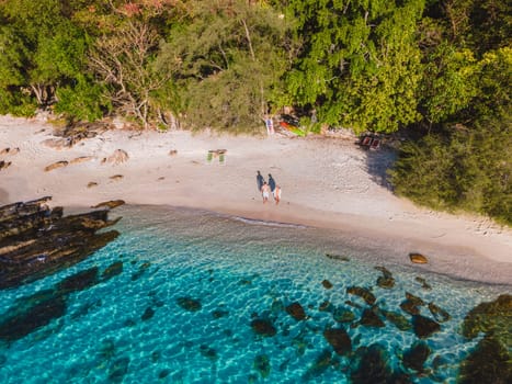 Koh Samet Island Thailand, aerial drone view from above at a couple of men and woman on the beach of Samed Island at sunrise in Thailand with a turqouse colored ocean and a white tropical beach