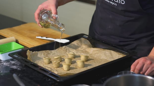 The cook puts the cooked dumplings out of the pan into a white plate.ART. A person adds a ready-made dish to the plate with a colander.
