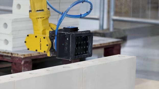 Industrial robotic machine at the industrial international exhibition. Close up of a robot putting a white brick in a layer of a wall, technologies for urban construction site.