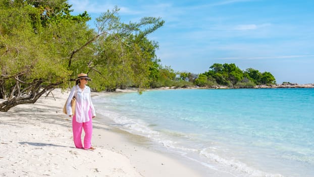 Asian woman walking on the beach of Koh Samet Island Rayong Thailand, the white tropical beach of Samed Island with a turqouse colored ocean