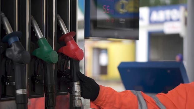 Oil, fuel nozzles hang on the machine in the petrol station. Clip. Close-up of a men's hand using a fuel nozzle at a gas station. Petrol station. Filling station. Petrol. Gasoline. Man holding a gasoline nozzle. Petrol pump.