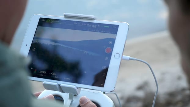 Close-up of man's hands with a remote control flying a small quadcopter toy at nature.