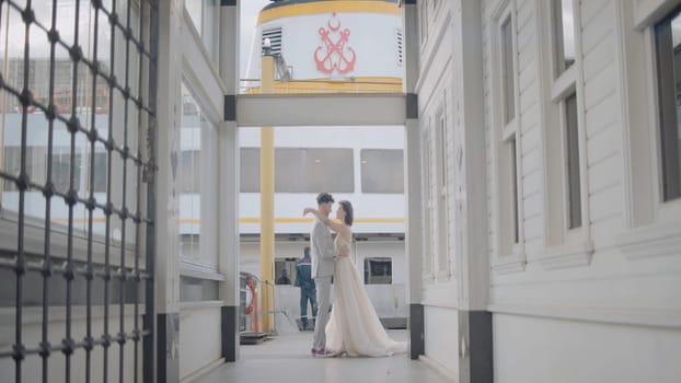 Newlyweds on background of pier. Action. Beautiful newlyweds pose between city buildings. Stylish newlyweds hug on background of city pier in cloudy weather.