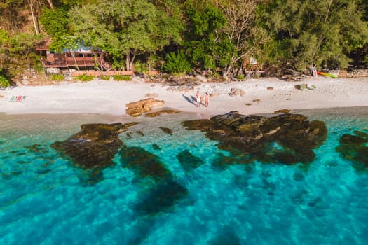 Koh Samet Island Thailand, aerial drone view from above at a couple of men and woman on the beach of Samed Island in Thailand with a turqouse colored ocean and a white tropical beach