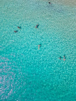 aerial drone view from above at people swimming in the ocean at the Samed Island in Thailand, with a turqouse colored ocean and a white tropical beach view at Koh Samt Thailand