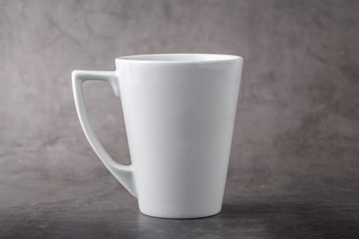 Empty white porcelain cup on gray stone background