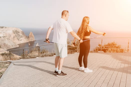 Happy Middle aged couple or friends practicing nordic walking in park near sea. Mature couple with trekking poles walking, practicing Nordic walking outdoors. Aging youthfully and sport concept.