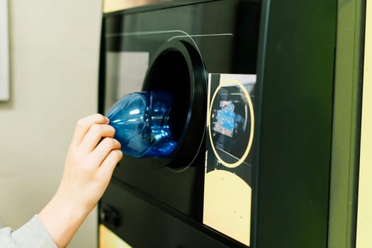 Reverse vending recycling machine that dispenses cash. Man hand puts plastic bottle to machine