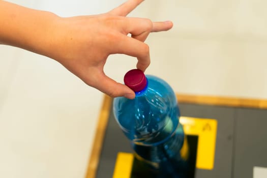 Selective focus close up hand throwing empty plastic bottle in the recycling garbage trash or bin