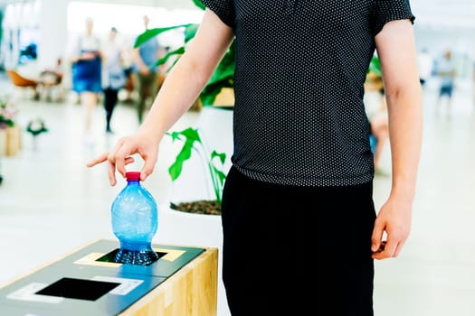 Selective focus close up hand throwing empty plastic bottle in the recycling garbage trash or bin