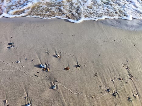 Yellow sand, pebbles and a transparent wave as a background, texture. Abstract pattern, place for text and copy space