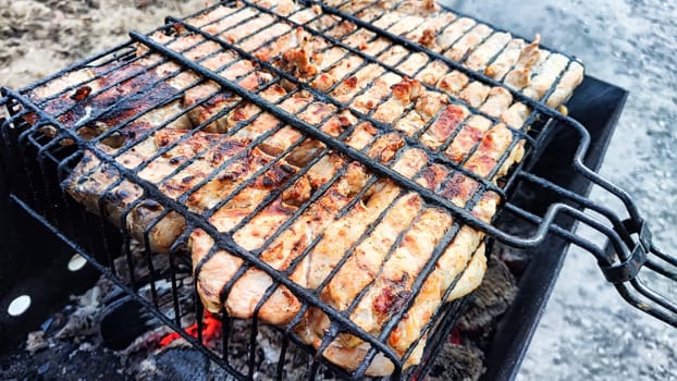 Pieces of shish kebab on iron grill over the coals over the grill. Delicious fried meat