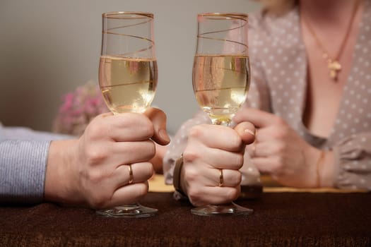 Hands Man and woman sitting at table with glasses of champagne. Hands with rings on the fingers. Newlyweds and divorce. Quarrel, swearing, hatred, holiday, wedding, newlyweds