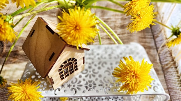 miniature toy house in grass and dandelion flowers, spring natural background. symbol of family. mortgage, construction, rental, property concept. Eco Friendly home. soft selective focus. copy space