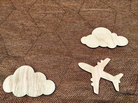 Wooden toy airplane and clouds on a brown background. The concept of traveling by plane. Tourism, travel, speed. Takeoff, landing. The crash, the storm