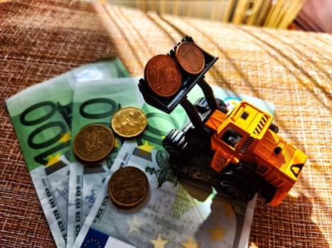 A small toy tractor or excavator on bundle of money. The concept of the high cost of technology. The possibility of earning money with construction machinery