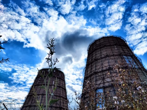 Big tower of CHPP close-up. White steam from wide pipe of CHP and blue sky. Industrial background. Huge pipes of thermal power plant produce steam for electric power. Strategically important object