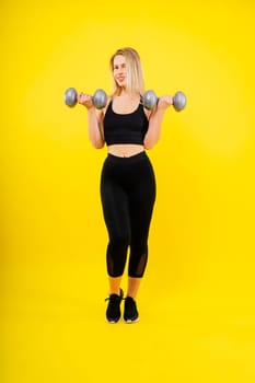 Muscular woman doing exercises with dumbbells on biceps. Photo of strong female isolated on studio