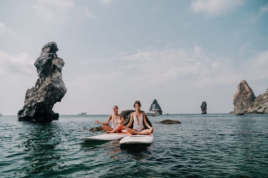 Woman sup yoga. Middle age sporty woman practising yoga pilates on paddle sup surfboard. Female stretching doing workout on sea water. Modern individual hipster outdoor summer sport activity