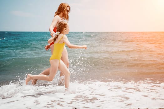 Happy loving family mother and daughter having fun together on the beach. Mum playing with her kid in holiday vacation next to the ocean - Family lifestyle and love concept.