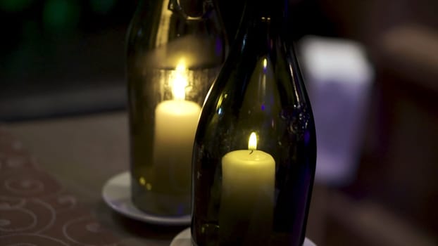 Decorative bottles with candles inside. Candles inside small bottle. Summer homemade decoration, glass jar and bottle, led candle flame light inside.