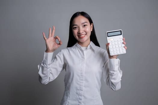 Portrait of a young accountant woman holding a calculator on a flat white background..