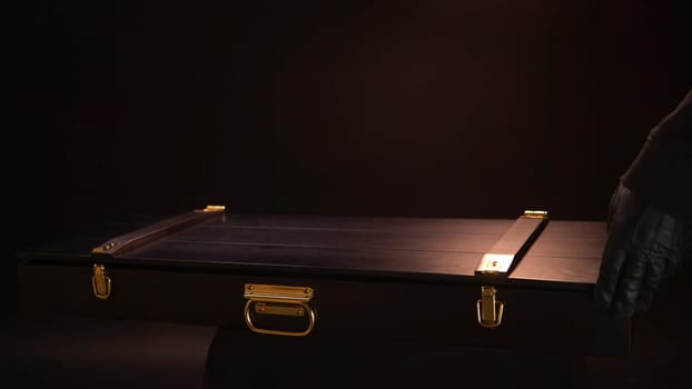 Close up of ancient valuable sward lying inside of wooden case with gold clasps. Hands in leather gloves open beautiful case with the antique exhibit, steel sabre inside.