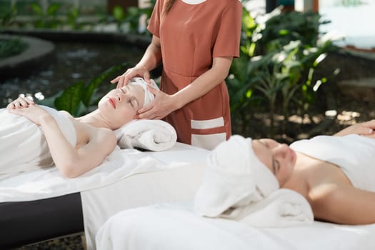 A portrait of two caucasian woman with beautiful skin having facial massage while falling the deep state of relaxation surrounded by outdoor natural and peaceful environment. Tranquility.