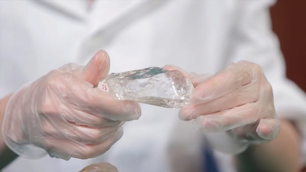 Natural stone amethyst or another mineral, stone. Wild amethyst in female hands in white gloves. Rock stone in hands.