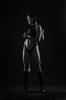 Slim tanned woman's body on dark grey background, studio shot