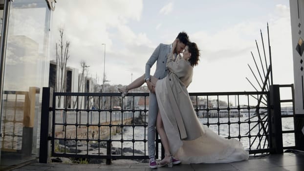 Pretty young bride and elegant groom standing outdoors on a windy day. Action. Just married couple posing in front of the camera