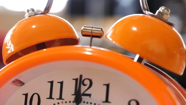 Close up of retro alarm clock going off on blurred background. Orange alarm clock details for waking up in the morning.